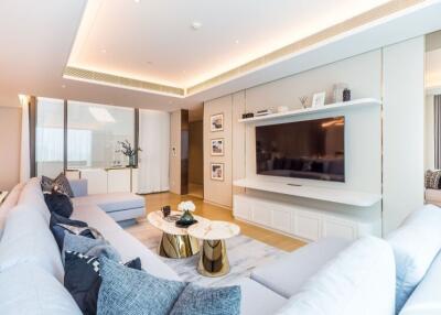 Modern living room with large flat-screen TV, white furnishings, and decorative accents