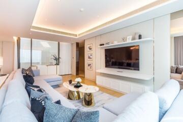 Modern living room with large flat-screen TV, white furnishings, and decorative accents