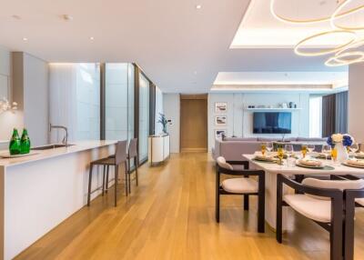 Modern open-plan living space featuring kitchen, dining area, and living room with wooden flooring and contemporary lighting.