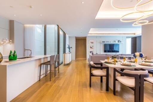 Modern open-plan living space featuring kitchen, dining area, and living room with wooden flooring and contemporary lighting.