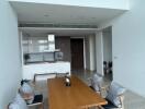 Modern dining area with wooden table and chairs, open kitchen in the background