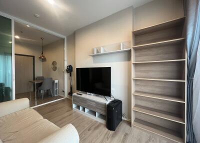 Modern living room with TV, shelving, and view into dining area