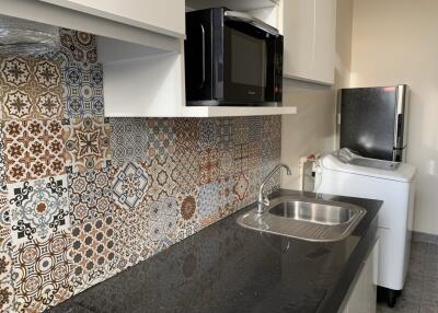 Modern kitchen with patterned tile backsplash, black countertop, and appliances