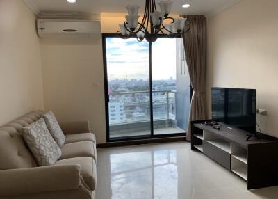 Modern living room with a sofa, TV, chandelier, and large window with city view