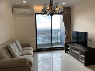 Modern living room with a sofa, TV, chandelier, and large window with city view