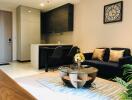 Modern living room and kitchen with black sofa, glass coffee table, and wall clock