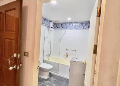 Bathroom with open wooden door revealing an interior featuring a bathtub, toilet, and washing machine