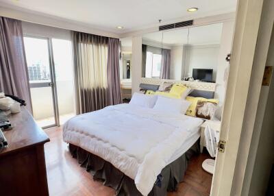 Modern bedroom with wooden flooring, large bed, and balcony