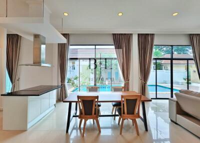 Open-plan kitchen and dining area with large windows and a view of the pool