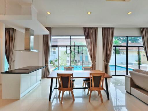 Open-plan kitchen and dining area with large windows and a view of the pool