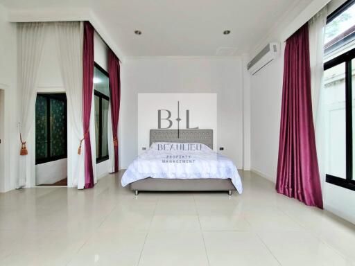 Spacious bedroom with large windows, curtains, and an elegant bed