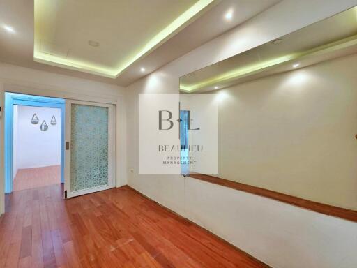 Well-lit hallway with wooden flooring and sliding door