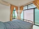 Bedroom with large windows and grey bedspread