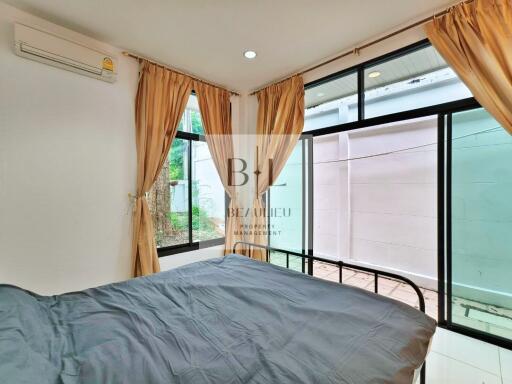 Bedroom with large windows and grey bedspread