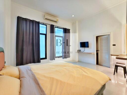 Spacious bedroom with bed, curtains, air-conditioner, and wall-mounted TV