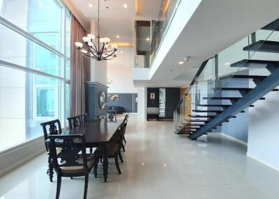 Modern dining area with glass staircase in a spacious, well-lit room