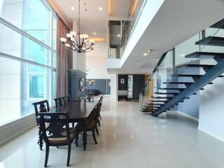 Modern dining area with glass staircase in a spacious, well-lit room