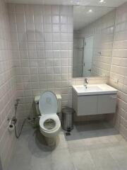 Modern bathroom with white tiles, toilet, and sink