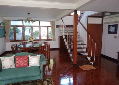 Well-lit living room with wooden flooring and a staircase