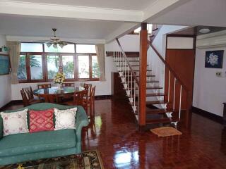 Well-lit living room with wooden flooring and a staircase