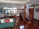 Well-lit living room with wooden flooring and a staircase