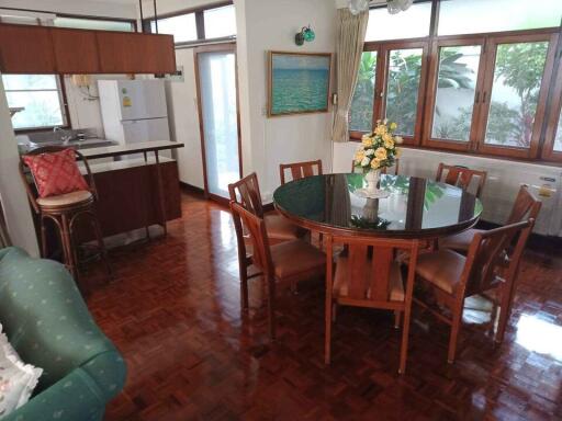 Dining room with a round table and six chairs, adjacent to a kitchen