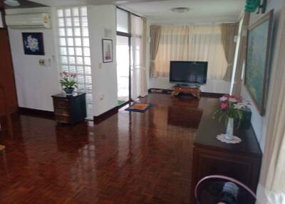 Spacious living room with hardwood floors, large window, and TV setup