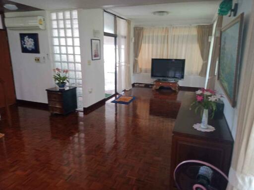 Spacious living room with hardwood floors, large window, and TV setup