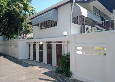 Exterior view of a two-story house with white walls and decorative fencing