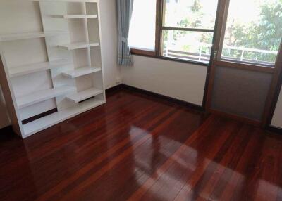 Bright empty bedroom with hardwood floor and a white bookshelf