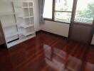 Bright empty bedroom with hardwood floor and a white bookshelf