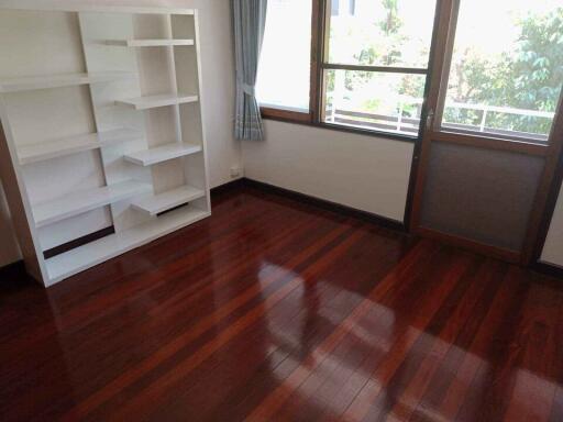 Bright empty bedroom with hardwood floor and a white bookshelf