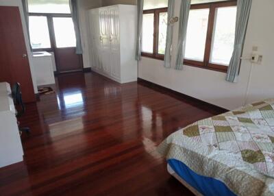 Spacious bedroom with wooden flooring, large windows, and built-in wardrobe