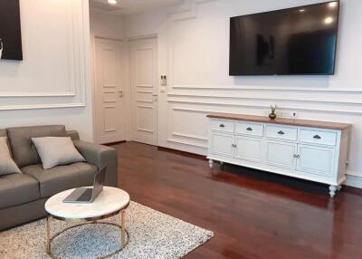 Living room with sofa, TV, and wooden flooring