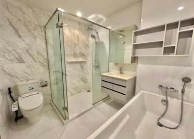 Modern bathroom with glass-enclosed shower, bathtub, toilet, and vanity with mirror and shelving