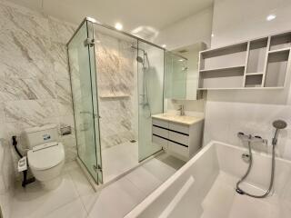 Modern bathroom with glass-enclosed shower, bathtub, toilet, and vanity with mirror and shelving