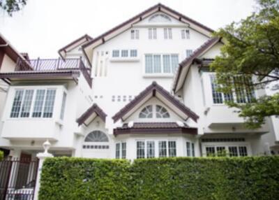 Front exterior view of a multi-story house with large windows and greenery