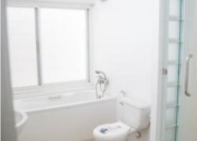 Bright and clean bathroom with a bathtub, toilet, and shower area with glass door