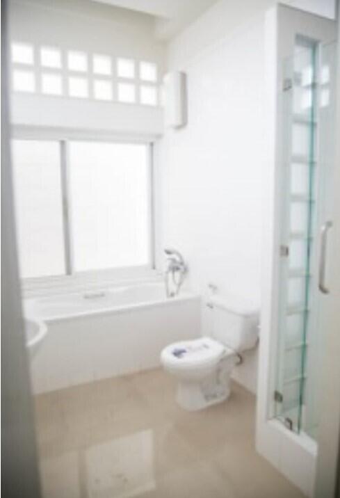 Bright and clean bathroom with a bathtub, toilet, and shower area with glass door