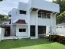 Exterior view of a white two-story house with a lawn