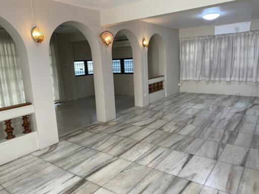 Spacious living room with marble flooring and arched doorways