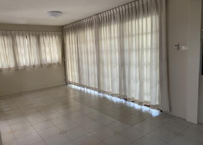 Spacious living room with tiled floors and large windows with curtains