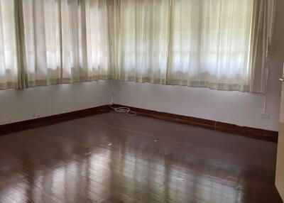 Empty living room with wooden flooring and large windows with curtains