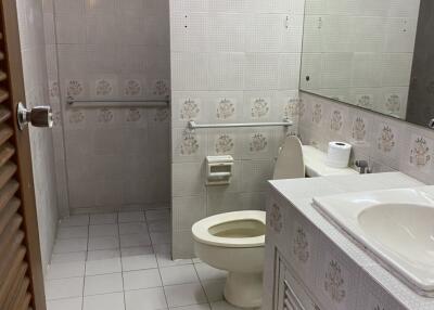 Bathroom with tiled walls and floor, a sink, toilet, and a vanity area.