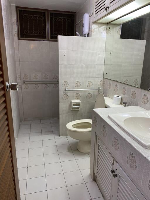 Bathroom with tiled walls and floor, a sink, toilet, and a vanity area.