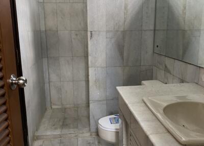 Bathroom with tiled walls and floors, shower area, sink, and toilet.