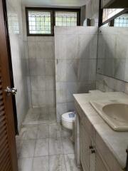 Bathroom with tiled walls and floors, shower area, sink, and toilet.