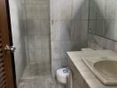 Bathroom with tiled walls and floors, shower area, sink, and toilet.