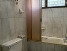 Marble-tiled bathroom with shower and toilet