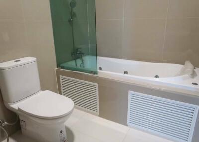 Bathroom with white ceramic toilet and bathtub with glass partition